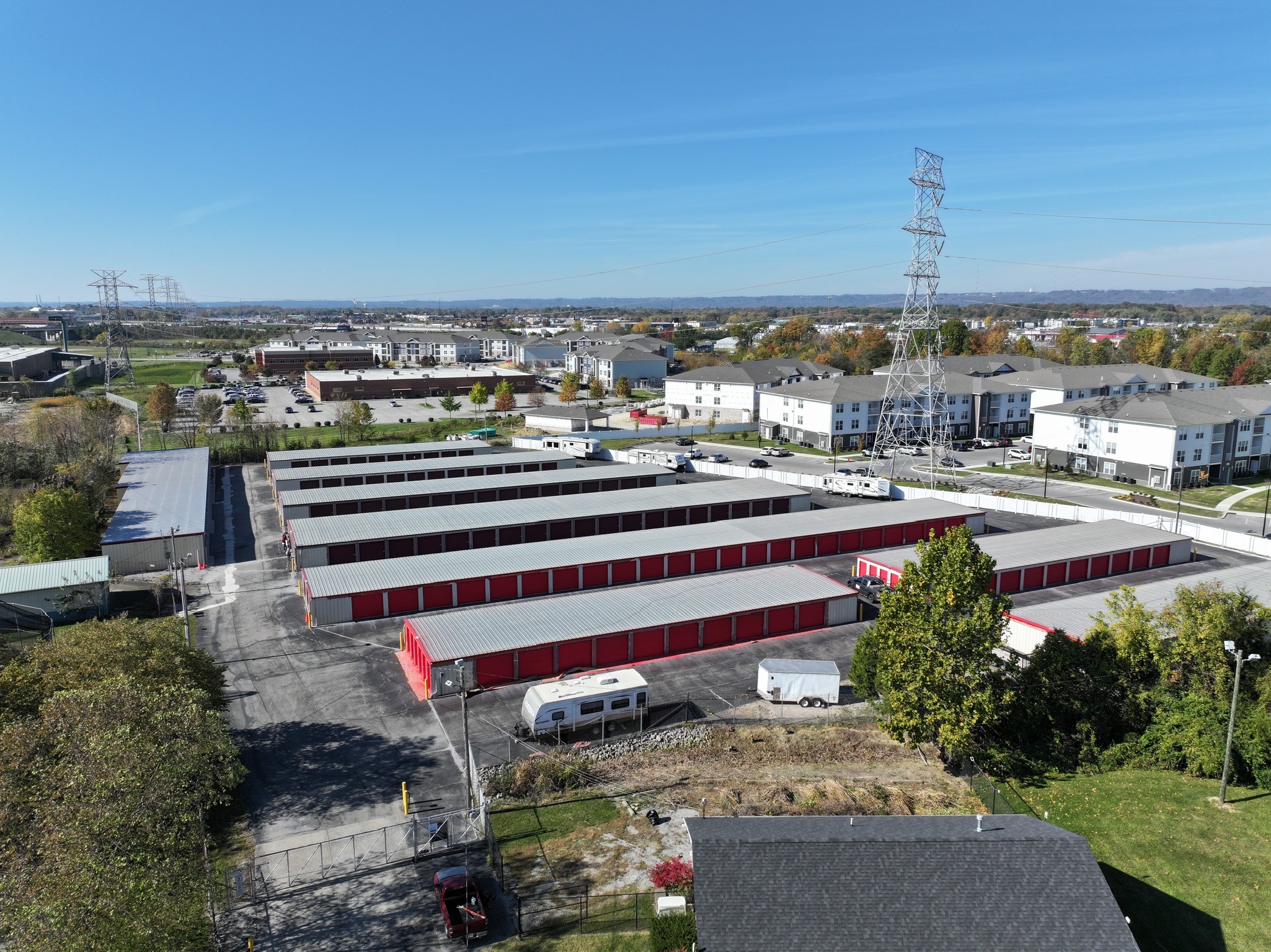 Aerial view of a self-storage facility in Jeffersonville with red and gray storage units in a clean, urban setting. The property includes gated access and nearby residential buildings, showcasing a convenient location for storage solutions.